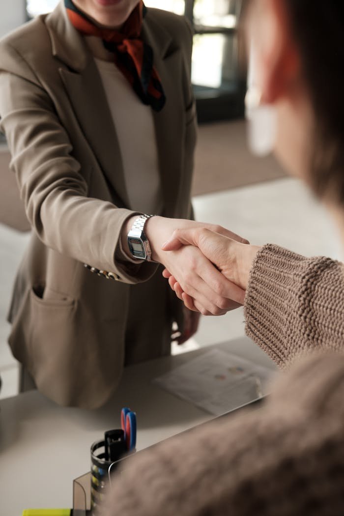 Services Two professionals shaking hands in an office, signifying a successful business agreement.